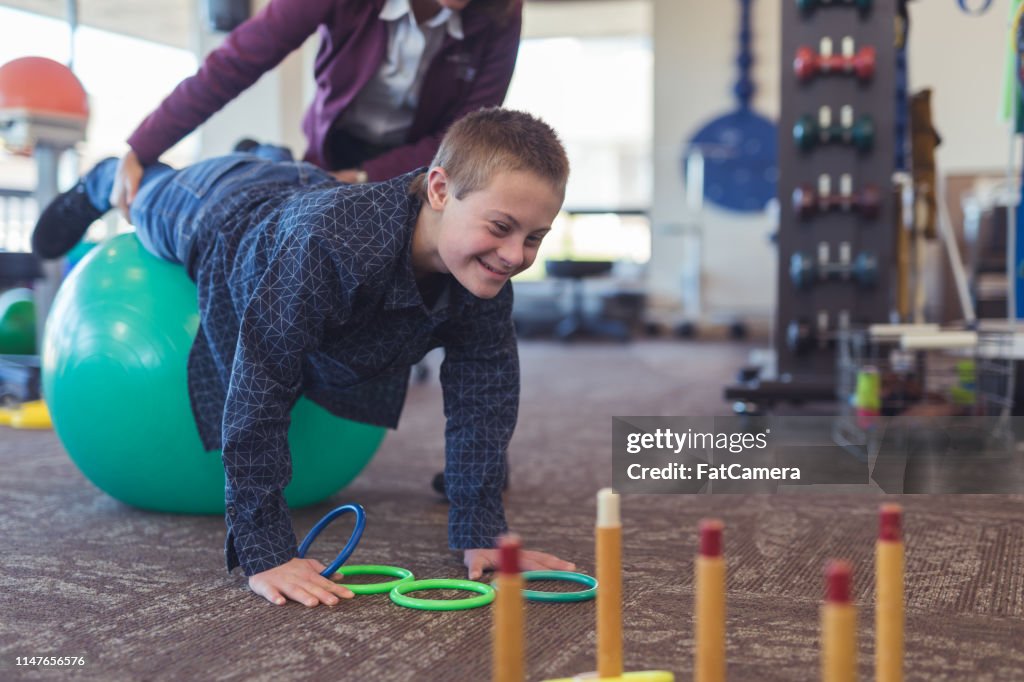 Een jongen doet workouts met een beroeps therapeut op een fysiotherapie kliniek