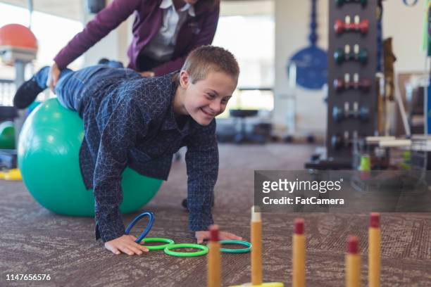 een jongen doet workouts met een beroeps therapeut op een fysiotherapie kliniek - match sport stockfoto's en -beelden