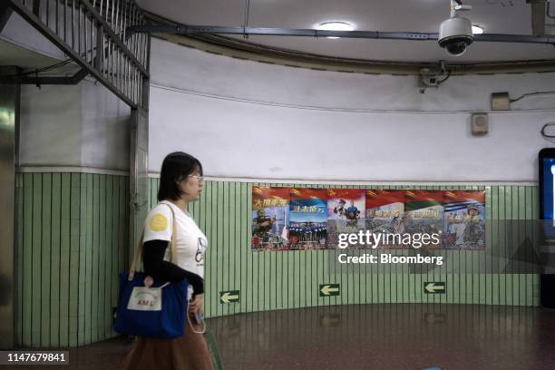 Commuter walks past recruitment posters for the People's Liberation Army inside a subway station in Beijing, China, on Friday, May 31, 2019. China...