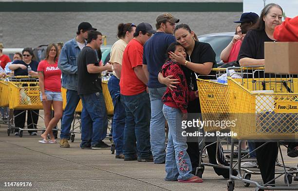 Blanca Lopez holds her daughter, Bianca Lopez, as they wait in line with others to receive food, clothes and other donated items for the people who...