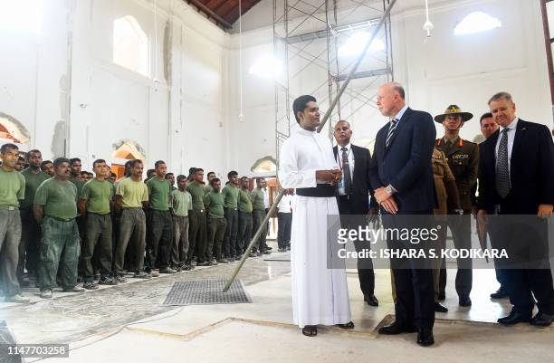 Australia's Home Affairs Minister Peter Dutton talks with Catholic priest Shameera Rodrigo look on during the Minister's visit to the bombed St...