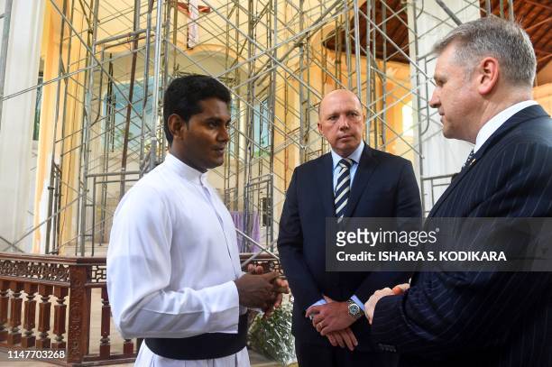 Australia's Home Affairs Minister Peter Dutton looks on as Catholic priest Shameera Rodrigo talks during the Minister's visit to the bombed St...