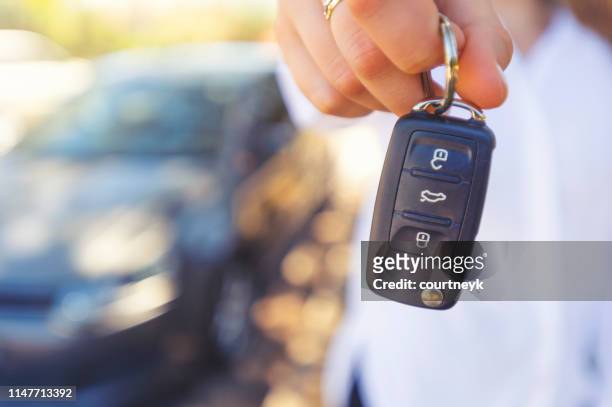 vendedor de autos femeninos entregando las llaves del auto nuevo - car rental fotografías e imágenes de stock