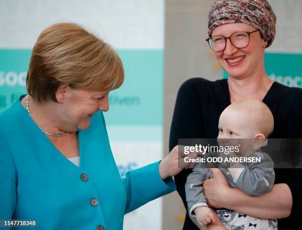 German Chancellor Angela Merkel and Wiebke Rasummi with her baby, from the Berliner initiative Rent a Jew, pose for the media during an awarding...
