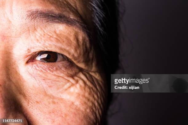 close-up of senior woman's eye - extreme close up face stock pictures, royalty-free photos & images