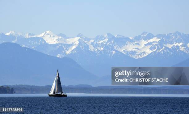 Boat sails on lake Starnberger See as in background can be seen an Alps panorama near Starnberg, southern Germany, where temperatures reached 28...