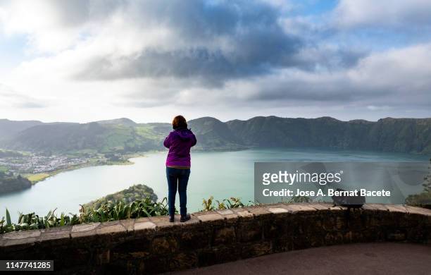 spanish ethnicity woman taking a picture, view of a lake from a viewpoint. sao miguel island, azores islands, portugal. - azores people stock pictures, royalty-free photos & images