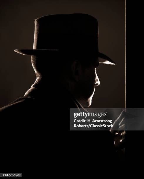 1950s 1940s DRAMATIC REAR PROFILE OF MAN IN FEDORA PEEKING AROUND DOOR VERY FILM NOIR