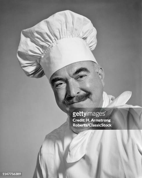 1960s SMILING MAN CHEF WITH MUSTACHE LOOKING AT CAMERA WEARING WHITE TOQUE CHEF'S HAT NECKERCHIEF AND LINEN UNIFORM JACKET