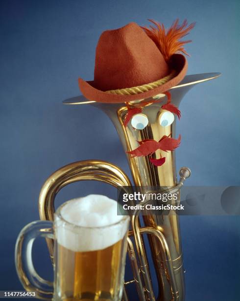 1970s HUMOROUS OKTOBERFEST STILL LIFE BRASS BARITONE HORN WITH BUG-EYED FACE MUSTACHE WEARING BAVARIAN HAT AND GLASS OF BEER