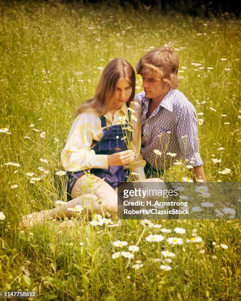 1970s ROMANTIC TEEN COUPLE IN FIELD OF DAISIES