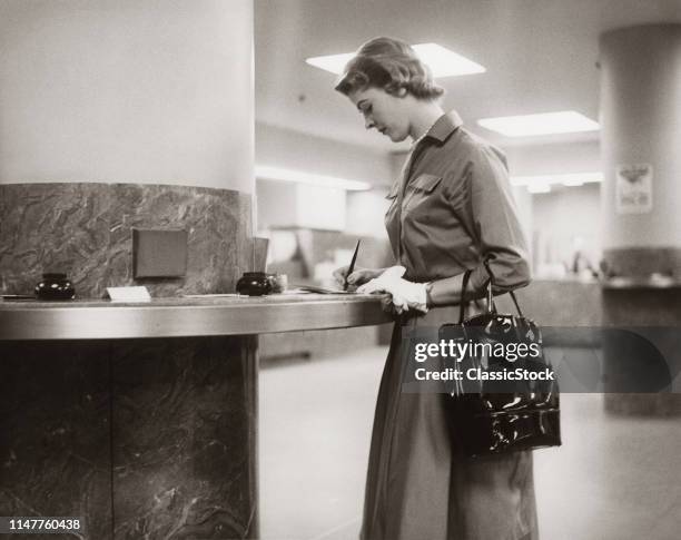 1950s 1960s WOMAN HANDBAG ON ARM GLOVES FILLING OUT DEPOSIT SLIP BANK COUNTER