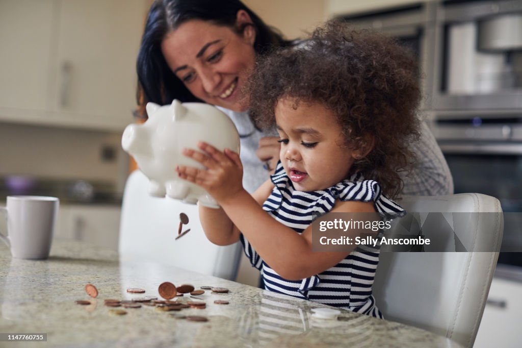 Mother and child getting money from a piggy bank