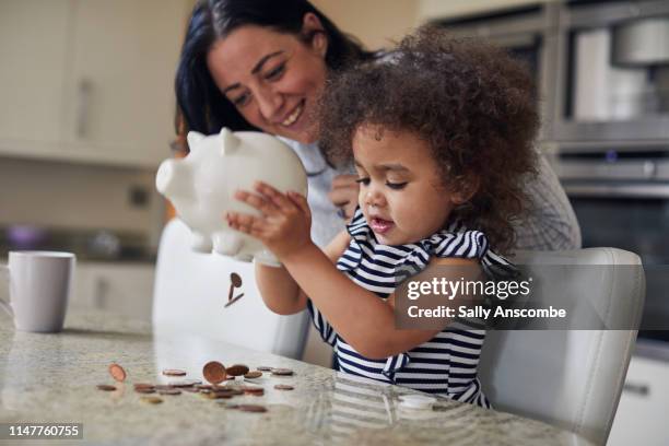 mother and child getting money from a piggy bank - save money stock pictures, royalty-free photos & images