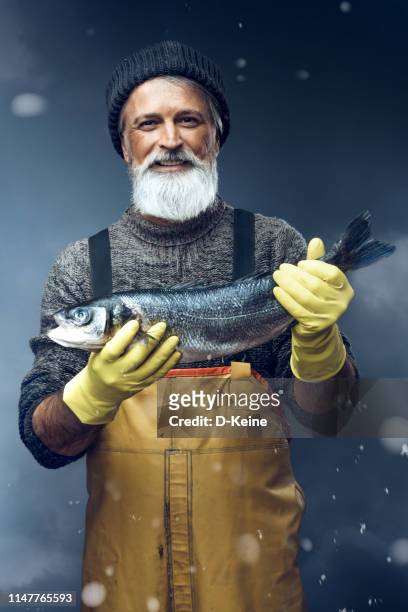 fischer mit einem großen fisch auf stürmischem hintergrund - angler fish stock-fotos und bilder