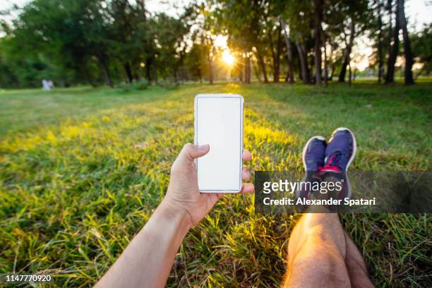 using smartphone in the park, personal perspective view - enkels over elkaar stockfoto's en -beelden