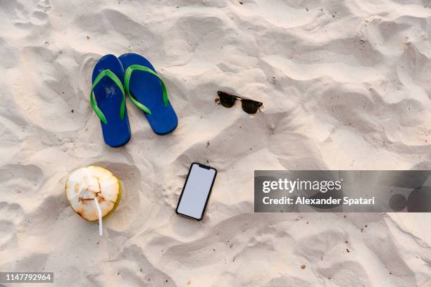 flip-flops, sunglasses, smartphone and fresh coconut on the sand, high angle view - coconut beach stock-fotos und bilder