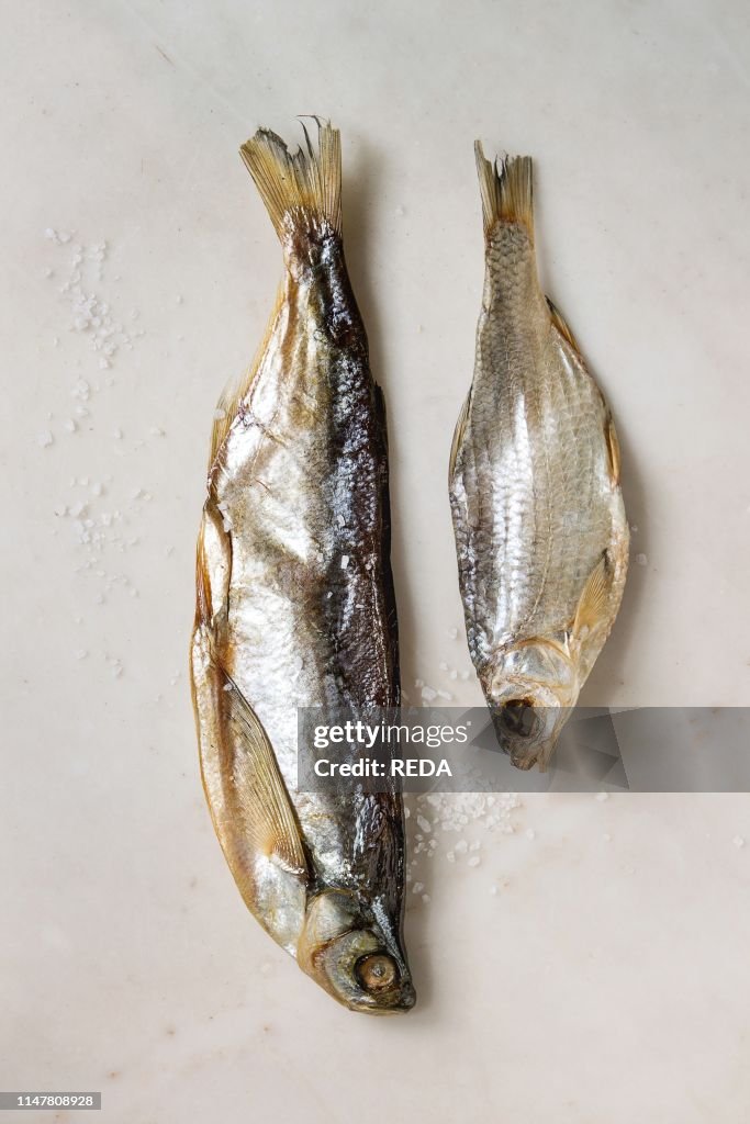 Dried fish or stockfish over white marble background. Flat lay. space
