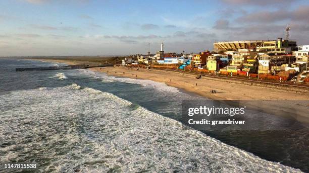 sweeping drone point of view of the beach and boardwalk near the international border wall in playas tijuana, mexico - tijuana stock pictures, royalty-free photos & images
