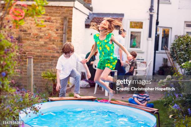 young girl leaping into a paddling pool - プール　庭 ストックフォトと画像