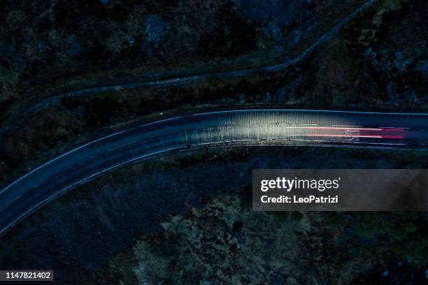 light trails in the night on a remote road in mountains - british high street stock pictures, royalty-free photos & images