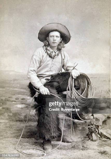 Cowboy Wearing Black Wooly Chaps, A Kerchief, Lariat In Hand, Spurs, Cowboy Boots, Holstered Revolver, And Great Cowboy Hat. Handsome Cowboy With...