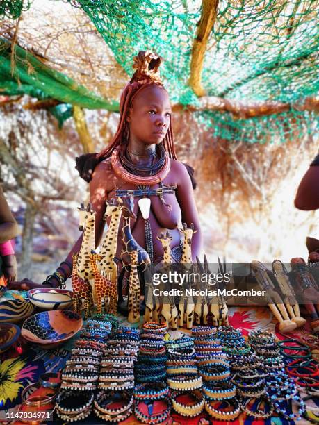 young himba woman at her market stall looking away - himba imagens e fotografias de stock
