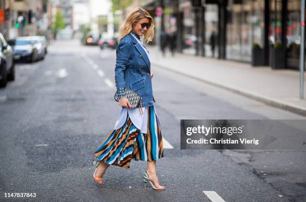 Gitta Banko is seen wearing a layering look containing, a blue transparent turtleneck top with white dots, long oversize striped blouse and a...