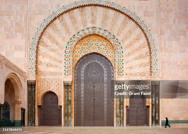 man passing main entrance to mosque. - モロッコ カサブランカ ストックフォトと画像