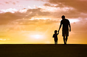 Father and son walking at sunset
