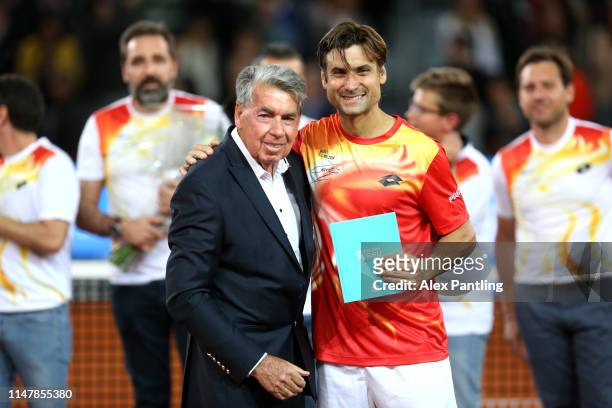 Manuel Santana presents a book to David Ferrer of Spain after playing his last ever match during day five of the Mutua Madrid Open at La Caja Magica...