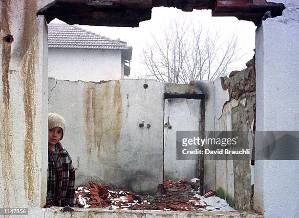 Visar Shala stares out from a neighbor's destroyed house at the road in the village of Kpolici i Ulet in Kosovo's Drenecia region Sunday Dec. 13,...