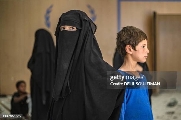 Displaced Syrians prepare to board a bus waiting outside the Al-Hol camp in northeastern Syria's Al-Hasakeh governorate on June 3 as Kurdish...