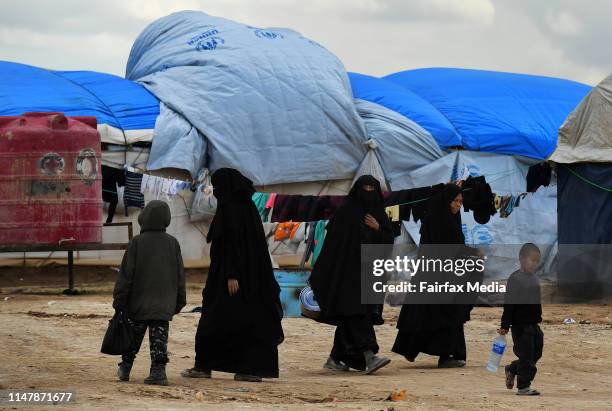 Women and children walk amongst the tents of the al-Hawl refugee camp in northern Syria, close to the Syria-Iraq border, April 2, 2019. The camp is...