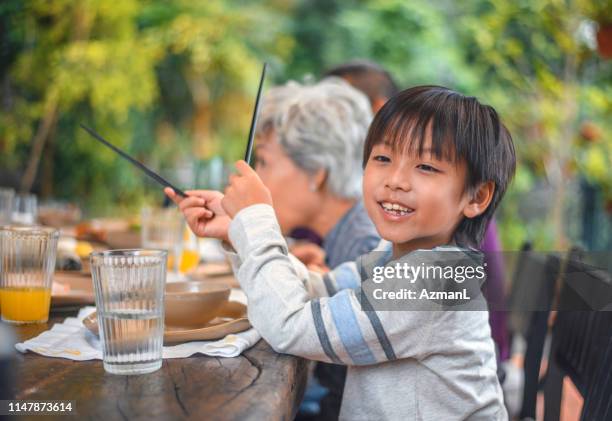 ダイニングテーブルで祖父母と座っているかわいい男の子 - chinese eating backyard ストックフォトと画像