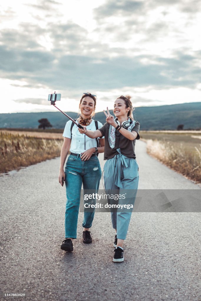 Happy friends with a selfie stick filming their adventure