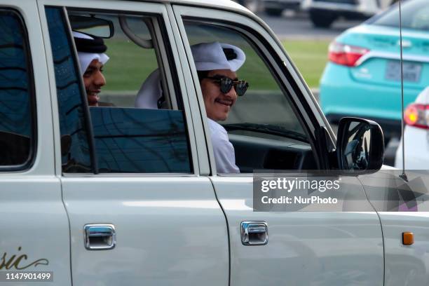 Two Qataris peer outside of a Land cruiser. During Ramadan before sunset Doha's corniche hosts a car parade where residents can show off their cars,...