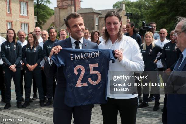 French President Emmanuel Macron poses with a French National Women's soccer team's jersey reading his name, next to France's head coach Corinne...