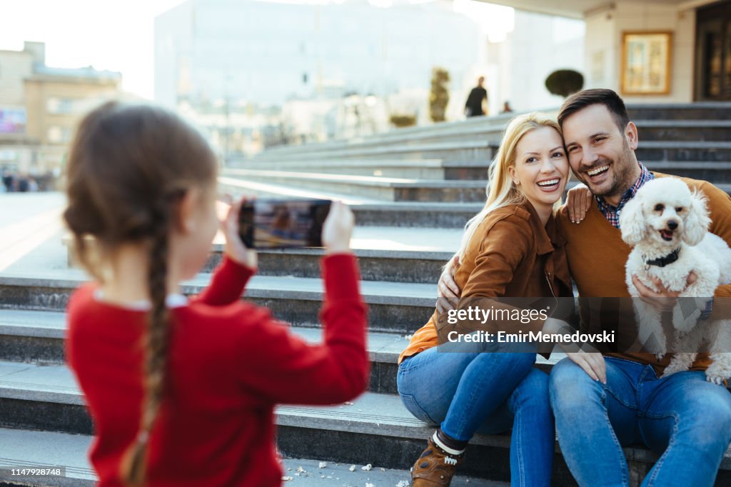 Daughter taking photo of her parents and dog in the city