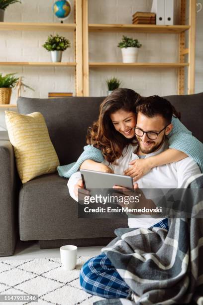 young couple using digital tablet at home - young couple shopping stock pictures, royalty-free photos & images