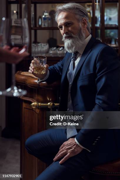 classy dressed senior man sitting in bar - whisky bar stock pictures, royalty-free photos & images