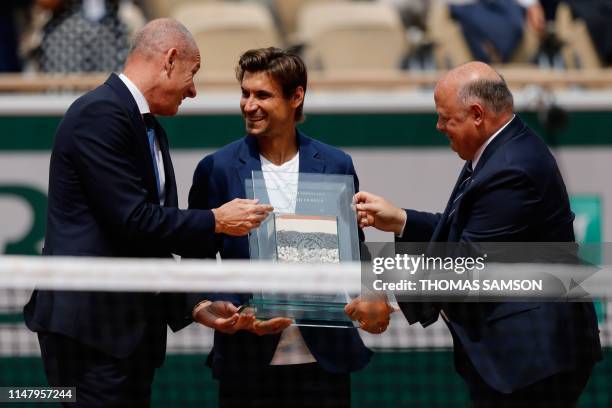 Former tennis player Spain's David Ferrer receives an award for his career by President of the French Tennis Federation Bernard Giudicelli and former...