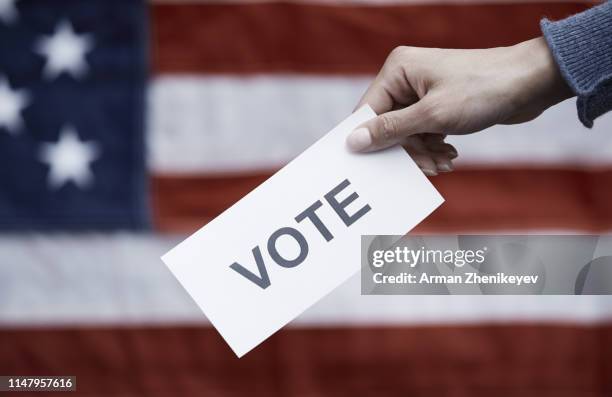 woman holding paper with vote text on american flag background - ballot paper stock pictures, royalty-free photos & images