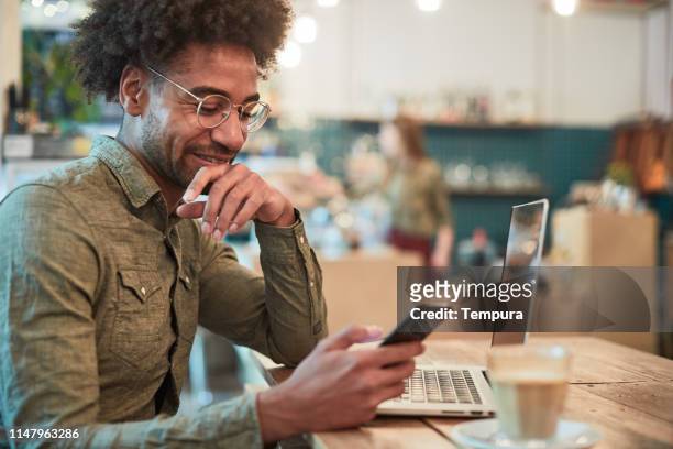 junger mann schaut sich seine finanzen in einem handy an. - mobile banking stock-fotos und bilder