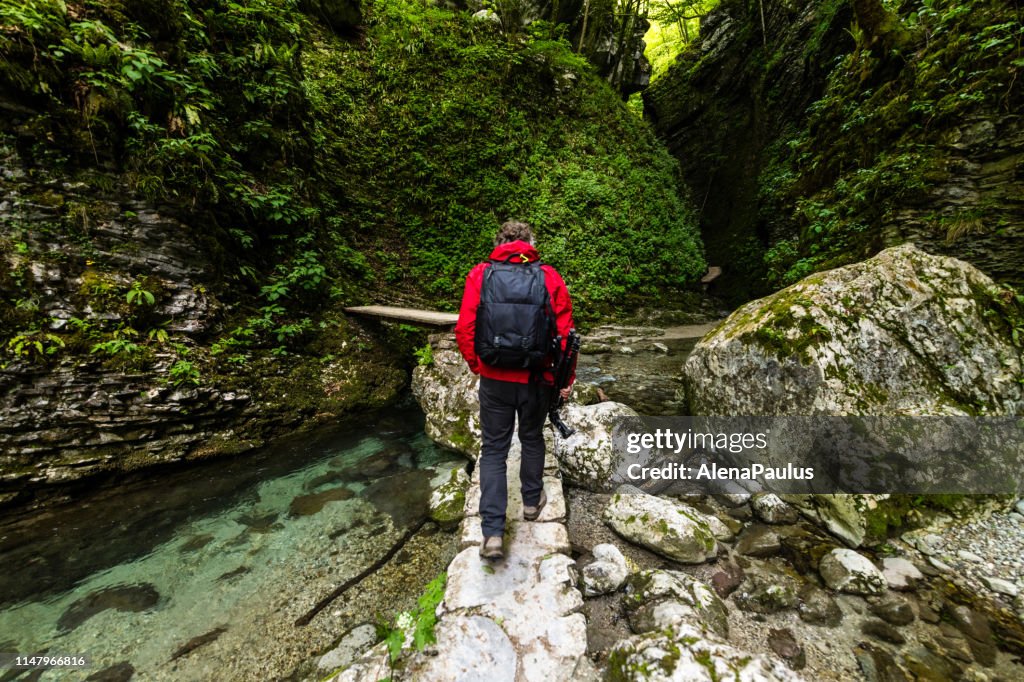 Man exploring the paths of the Amazing Kozjak waterfall in Julian Alps canyon near Kobarid, Slovenia