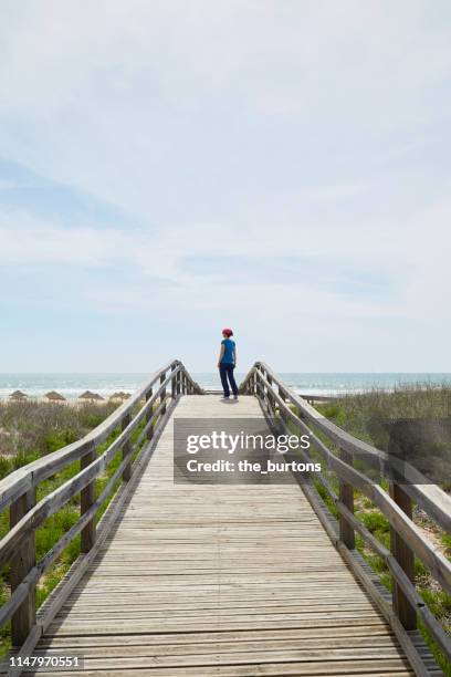 woman standing on boardwalk to the sea - alvor stock pictures, royalty-free photos & images