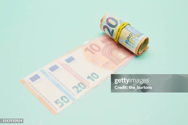 roll of euro banknotes on turquoise background - fajo de billetes de euro fotografías e imágenes de stock