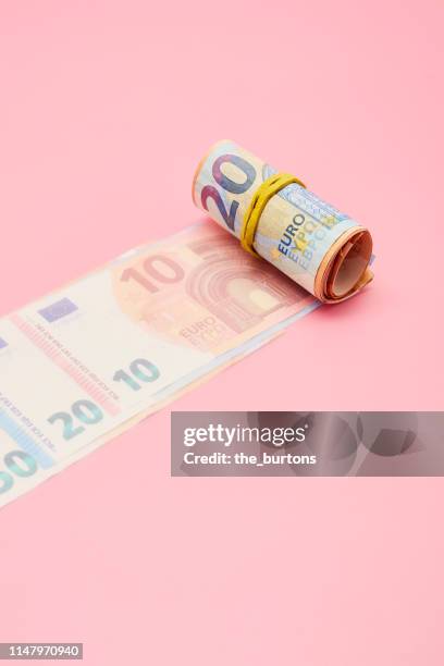 roll of euro banknotes on pink background - fajo de billetes de euro fotografías e imágenes de stock