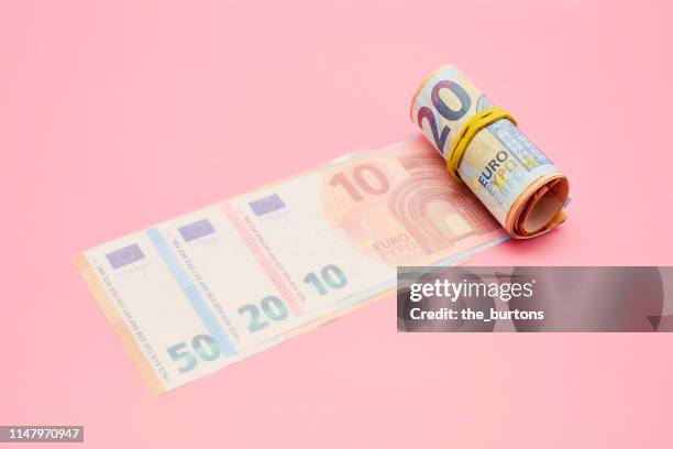 roll of euro banknotes on pink background - geldschein stock-fotos und bilder