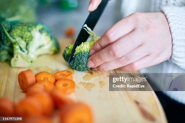 woman's hand slicing broccoli on wooden chopping board - chopping stock pictures, royalty-free photos & images